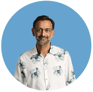 A headshot of Paul Grewal, Coinbase CLO, smiling in a floral button-up