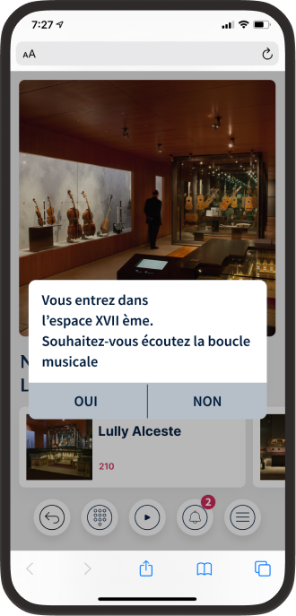 A smartphone displaying the museum’s guide with a pop-up message in French, asking if the user wants to listen to the musical loop of the ‘XVII century’ area. The background image shows stringed instruments on display.