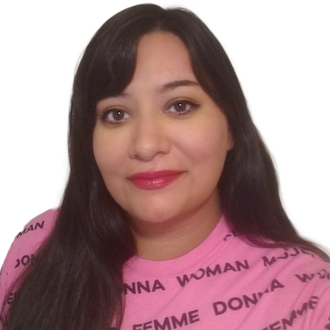 Zelma (she/her)—close photo of Latinx woman wearing a hot pink shirt that has different words for “woman” in Black lettering. She has long, dark hair, and dark pink lipstick.