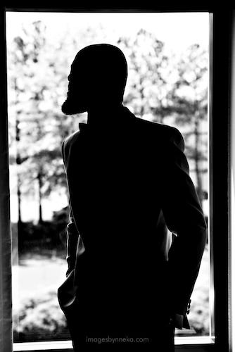 Silhouette of a pondering bald black man with a beard.