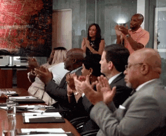 A GIF of people clapping in a meeting.
