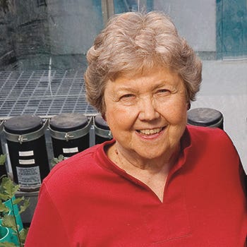 Headshot photo of Jean Langenheim with plants and solar cells behind her