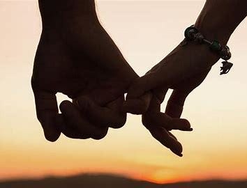 A picture of a couple holding hands. Only their hands are captured in the frame. The woman is wearing a bracelet and the background gives the vibe of a setting sun.