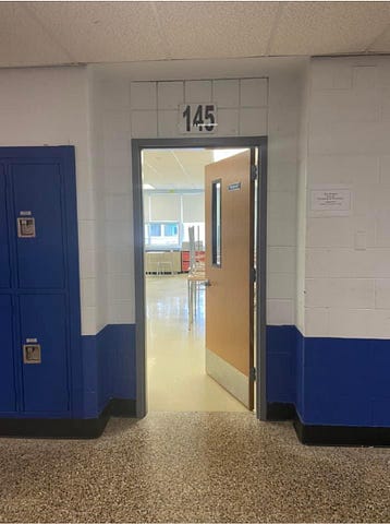 Classroom door in hallway showing empty room. Photo from author.