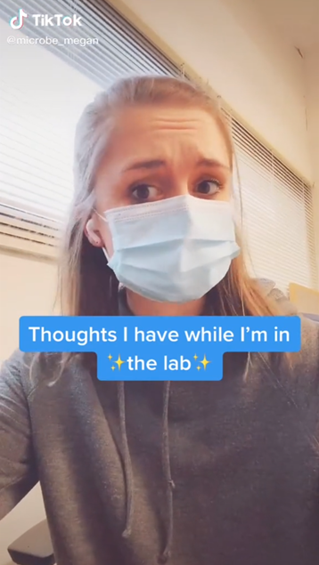 A screenshot of one of Megan’s TikTok videos. She is wearing a mask in the lab with a caption “Thoughts I have while I’m in the lab.”