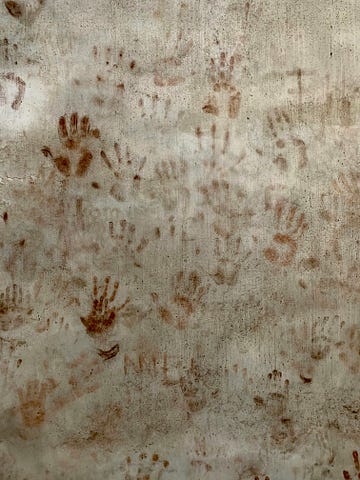 A white blanket with bloodstained handprints.