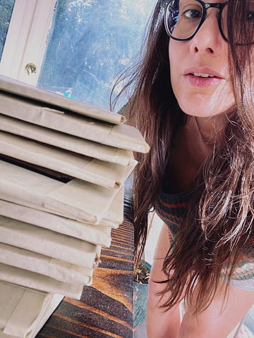 Woman artist stands next to a stack of packaged cardboards.