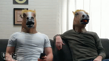 Dois homens com máscaras de cavalo se olhando e dando um high five.