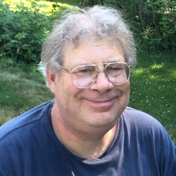 Man with glasses and curly gray hair smiling