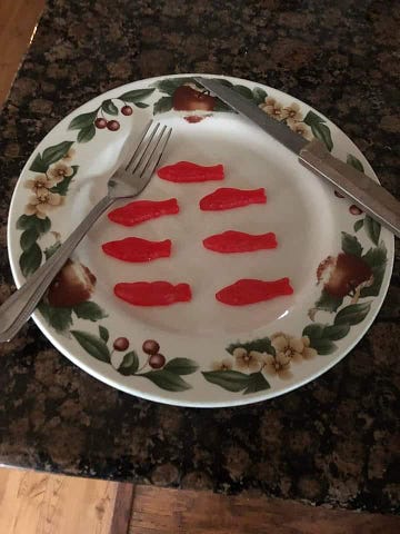 A Christmas plate with fork and knife. 7 gummie candy fishes included