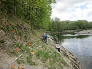 two biologists on a steep river bank