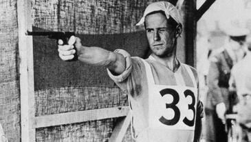 Man in a sports uniform aims a pistol at a target