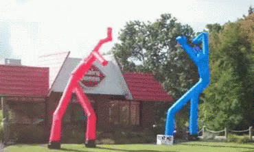 A gif of two dancing balloon people in front of a Dairy Queen.