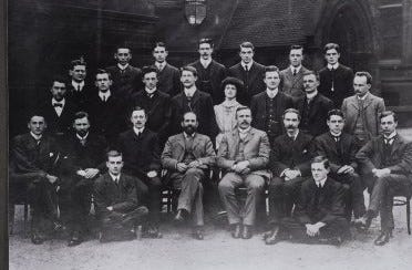 Black and white photograph of the University of Manchester Physics staff seated and standing over three rows.