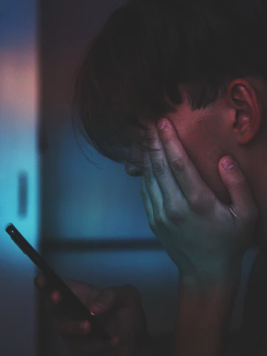 A boy crying while using his phone