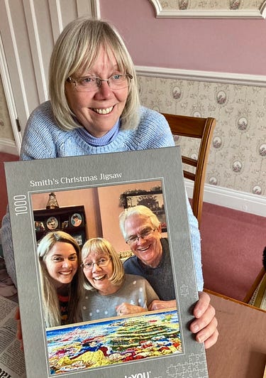 My Mum posing with this years Christmas jigsaw — a picture of us completing last years one.