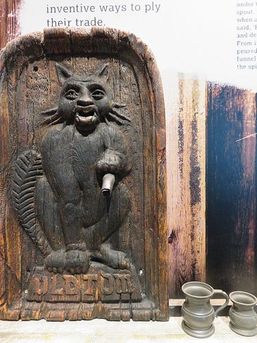 An old gin vending device known as a Puss and Mew. A metal cat statue with a spout under the left paw.