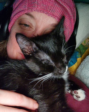 Little kitten laying on my smiling face. She is nearly all black, with a dot of white by her nose!