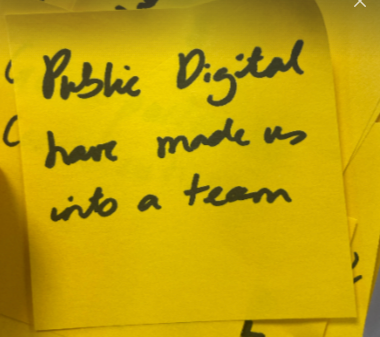 A yellow post-it note with the handritten note “Public Digital have made us into a team.”