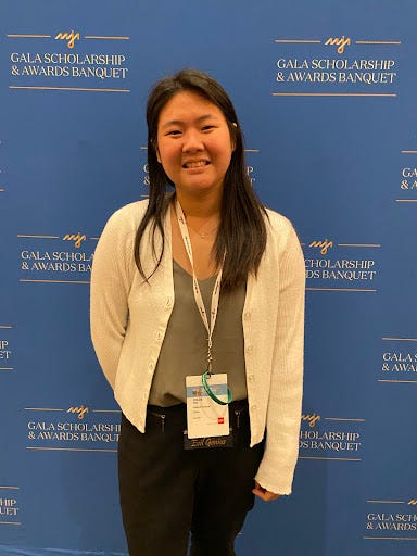 woman standing in front of background that says AAJA Gala Scholarship and Awards Banquet