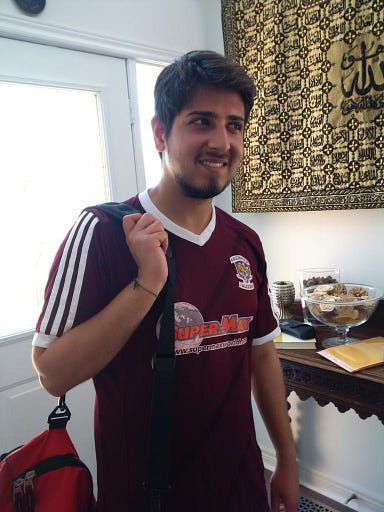 An old photo of me in a soccer jersey and with a gym bag swung over my arm in the foyer of my old house.