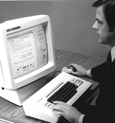 A man sitting at a Xerox Star workstation, using its graphical user interface.