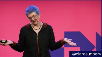 Clare speaking during this video — arms spread