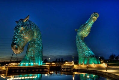 Two massive metal sculptures of horses heads in the night sky