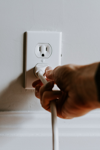 A person trying to plug a white cord.