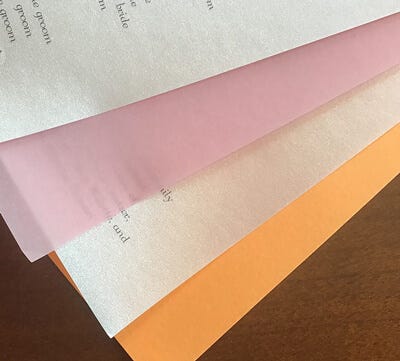 Sheets of metallic, translucent pastel and dayglo papers assembled together for a wedding program.