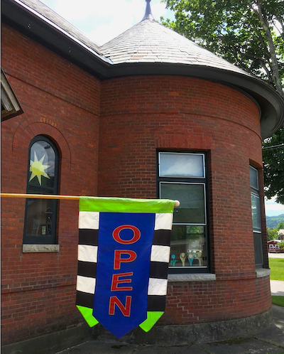 open flag hanging outside of a brick building with a rounded section