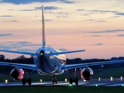 Rear view of a jet on a runway at sunset.