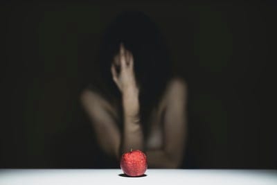 A woman covering her face with a red apple