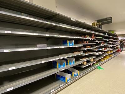 Picture of largely empty supermarket shelving with a few empty product boxes lying untidily in the shelves.