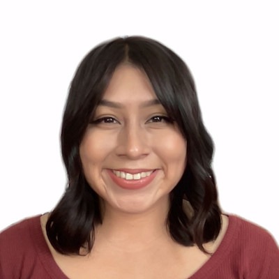 Photo of Yolis, a Hispanic woman, from the chest up. She is looking at the camera with an open-lipped smile. She is wearing a burgundy top. Her short brown curls are brushing both shoulders.