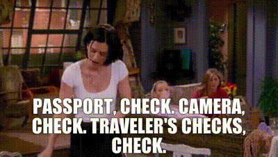 Gif animado da personagem Monica Geller da série Friends: ela coloca itens na bolsa, falando o nome do item e a palavra “check” depois. Passaporte: check! Câmera: check! Ela veste blusa branca e uma calça preta e Rachel e Phoebe estão em segundo plano, na sala roxa da casa da amiga.