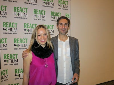 Malik Bendjelloul in grey jacket and white shirt and unidentified blonde woman in fuschia top with black fur ruff stand in front of white background with green and black text saying React to Film.
