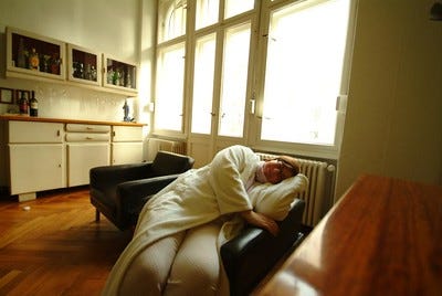woman wearing robe and pajamas sleeping sideways in a chair