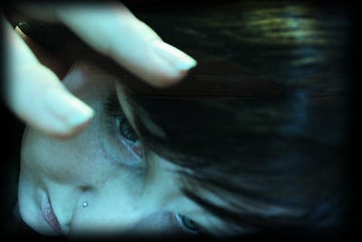 Close-up of a female-looking face and fingers with artistic features conveying a trapped feeling
