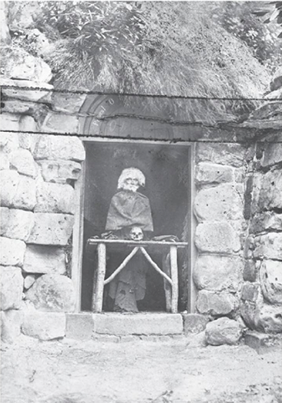 A black-and-white photo of the automaton, dressed as a hermit, in the doorway of the hermitage.