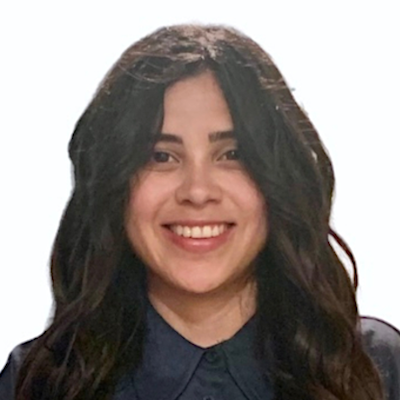 A headshot of Joslyn, a brown-eyed Latina woman smiling on a simple white background. She is looking at the camera with an open-lipped smile. She has dark brown hair and is wearing a deep teal, button-up, collared shirt.