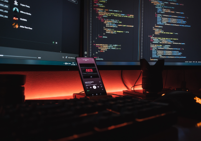 Two monitors with a phone docked in front with a red light in the backdrop