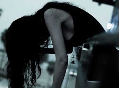 A depressed or drunk girl standing bent down on balcony