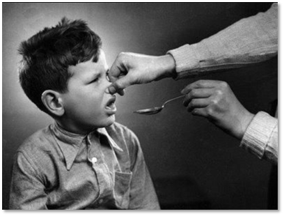 Vintage black and white image of a child being fed codliver oil by spoon with his nose being held.