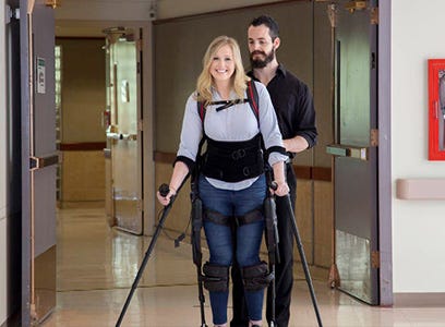 Woman walking with the assistance of robotic exoskeleton and crutches.