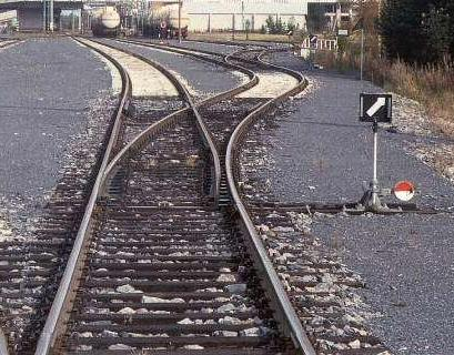 A singular line of railroad track that splits into two paths after the dividing railroad switch