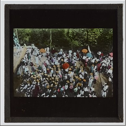 Large crowd from above with many hats and umbrellas.