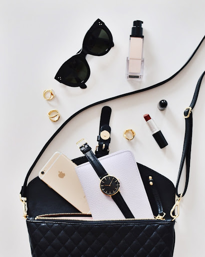 Aesthetic image with everyday objects, including sunglasses, perfume, ornaments, makeup, wrist watch and a tote bag