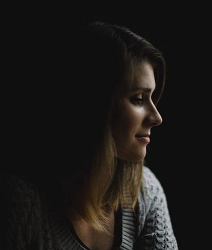 Photo of a white woman in profile in front of a black background.