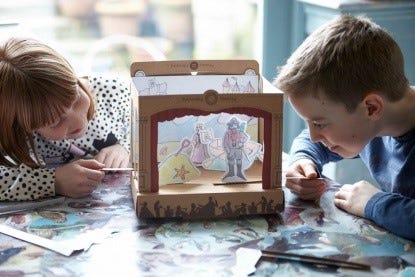 Girl and boy making a cardboard pop up theatre on a table